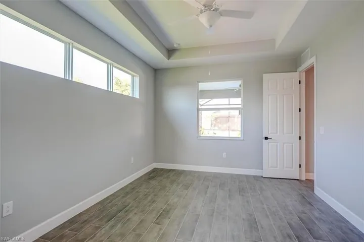 Empty room with plenty of natural light, ceiling fan, a tray ceiling, and hardwood / wood-style floors