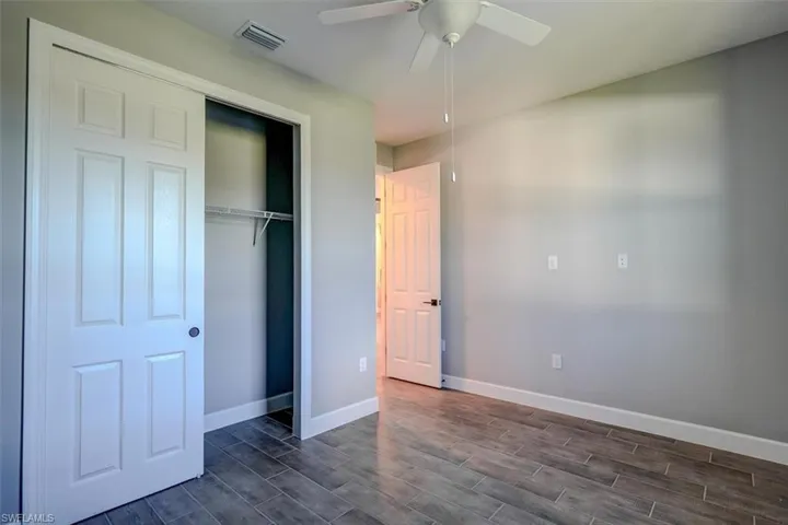 Unfurnished bedroom featuring dark hardwood / wood-style floors, a closet, and ceiling fan