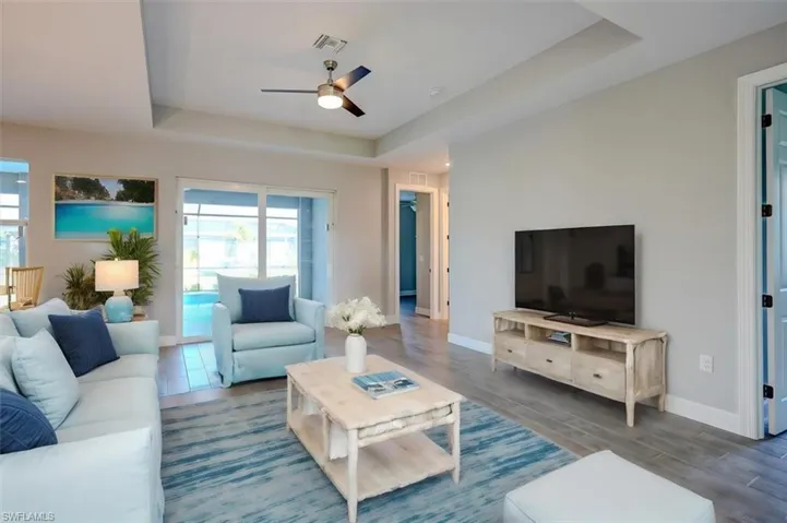 Living room featuring dark hardwood / wood-style flooring, ceiling fan, and a raised ceiling