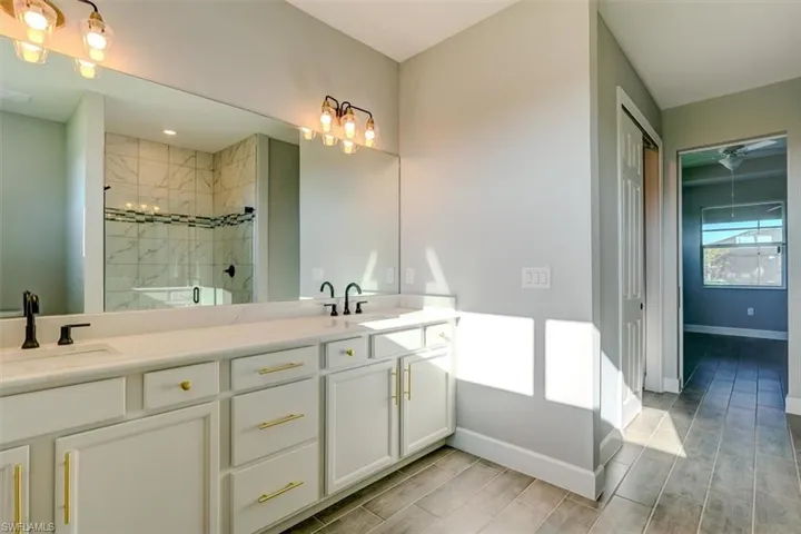 Bathroom featuring tiled shower, double sink, and large vanity