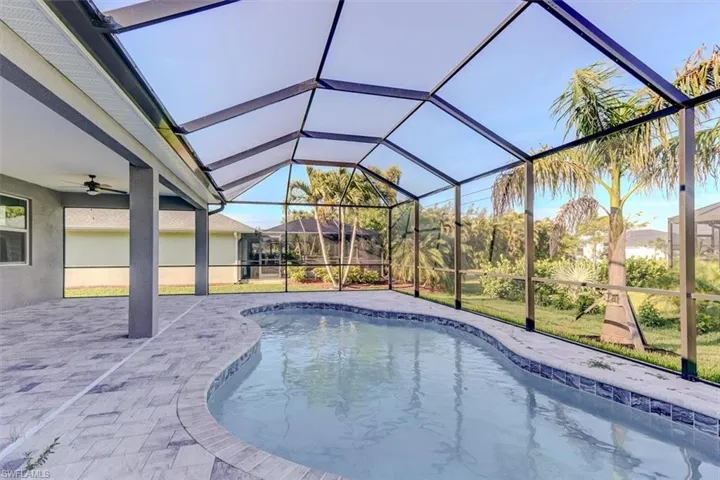 View of swimming pool with a patio area, glass enclosure, and ceiling fan