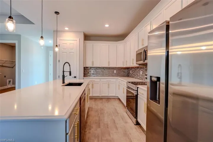 Kitchen featuring light hardwood / wood-style flooring, an island with sink, stainless steel appliances, backsplash, and sink