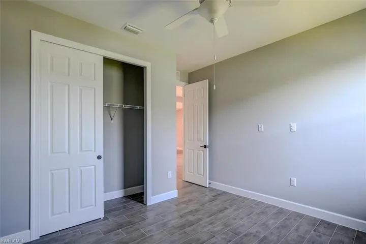 Unfurnished bedroom featuring a closet, ceiling fan, and dark hardwood / wood-style flooring