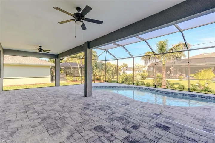 View of swimming pool with a patio, glass enclosure, and ceiling fan