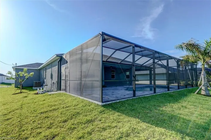 Rear view of property with a pool, a lawn, glass enclosure, and central AC unit