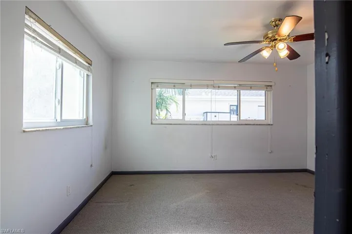 Spare room with carpet, plenty of natural light, and a ceiling fan