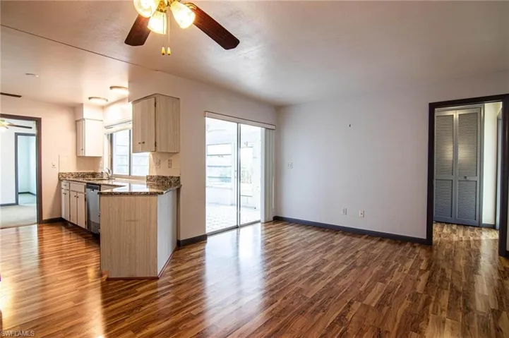 Kitchen with a ceiling fan, dark wood-style floors, dark stone counters, decorative backsplash, and stainless steel dishwasher