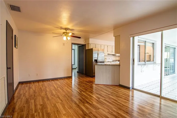 Kitchen featuring stainless steel refrigerator with ice dispenser, a ceiling fan, light wood-style flooring, open floor plan, and white range with gas stovetop