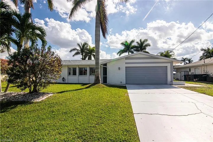 Ranch-style house featuring driveway, an attached garage, a front yard, and brick siding