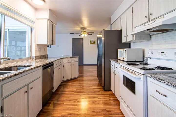 Kitchen featuring white appliances, light wood-type flooring, light stone countertops, and a ceiling fan