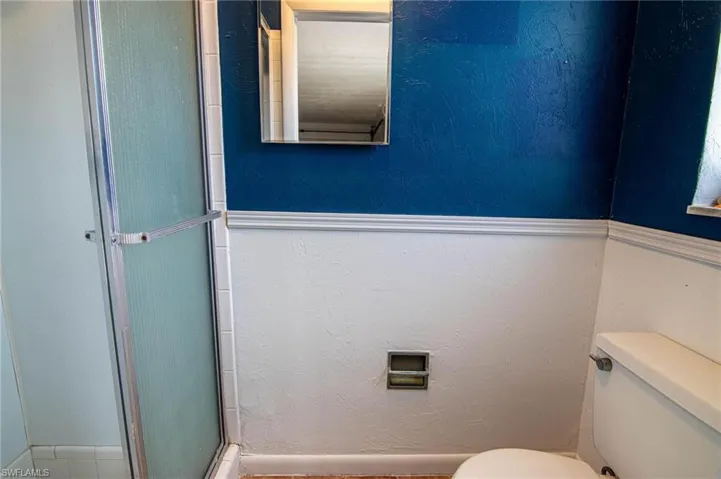 Full bath with an enclosed shower and a textured wall