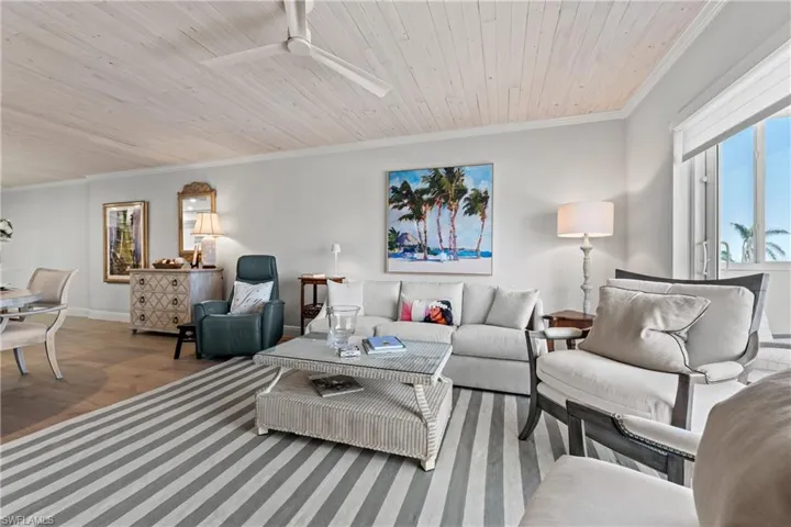 Living room with hardwood / wood-style floors, crown molding, ceiling fan, and wooden ceiling