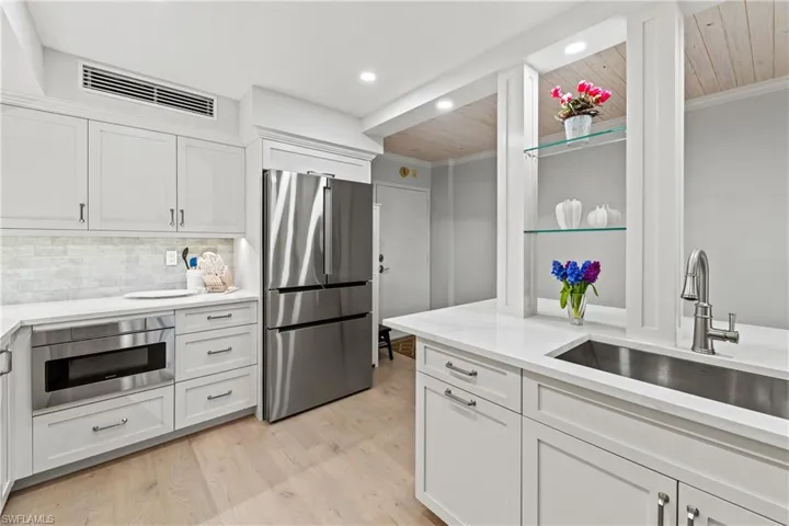 Kitchen with white cabinetry, backsplash, stainless steel refrigerator, and wooden ceiling