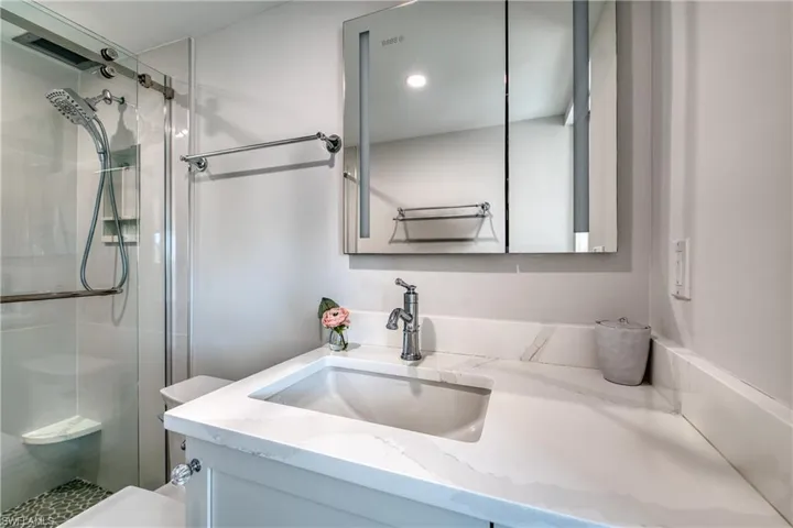 Bathroom featuring a shower with shower door, toilet, and vanity