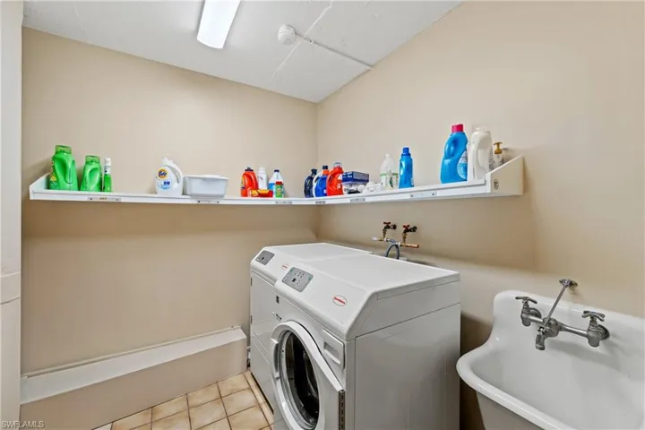 Washroom with washing machine and dryer, light tile patterned floors, and sink