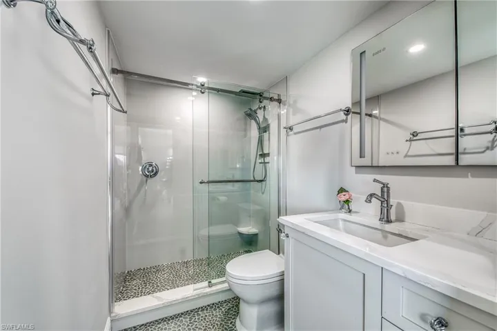Bathroom featuring vanity, toilet, and a shower with door