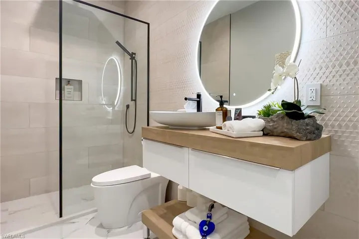 Bathroom with toilet, tiled shower, vanity, and tile patterned floors