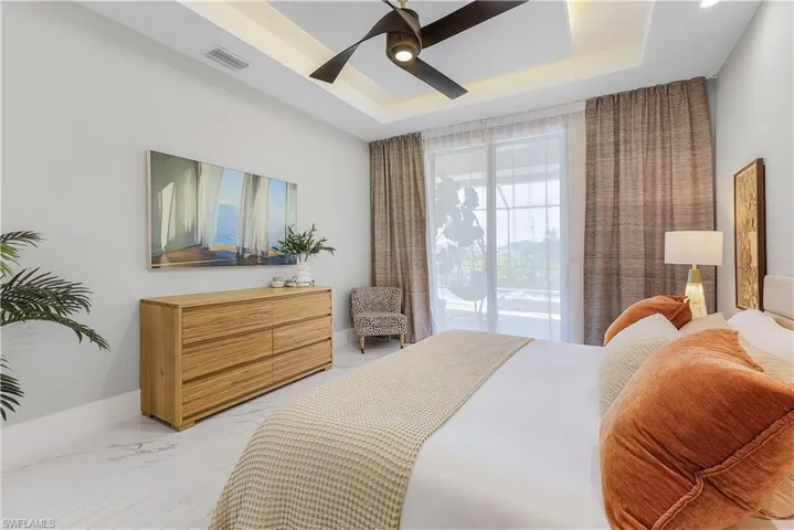 Bedroom featuring ceiling fan, a tray ceiling, and access to exterior