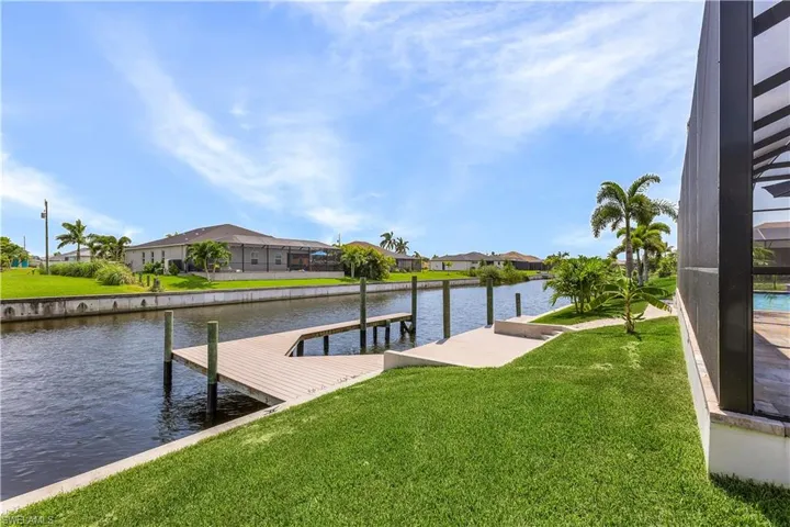 Dock area with glass enclosure, a water view, and a yard