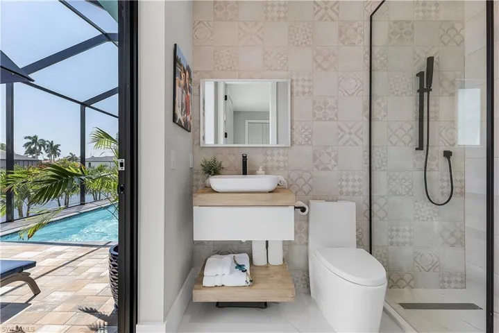 Bathroom with tile walls, tile patterned floors, tiled shower, and a wealth of natural light