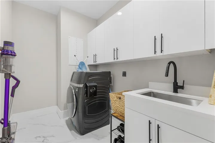Laundry area featuring sink, washer / dryer, and cabinets