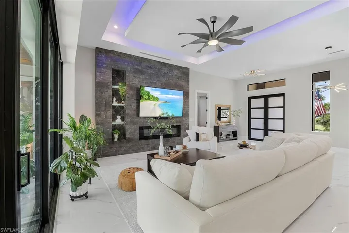 Tiled living room with tile walls, a raised ceiling, and ceiling fan