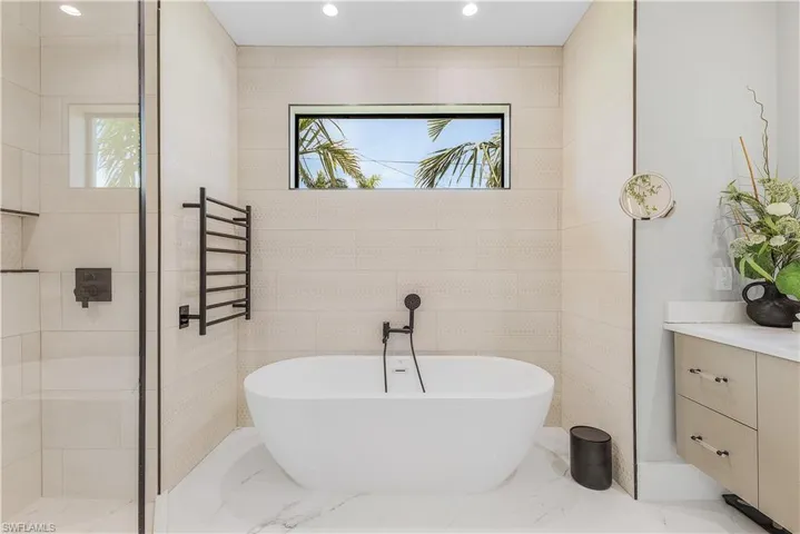 Bathroom with radiator heating unit, plenty of natural light, tile patterned floors, and vanity