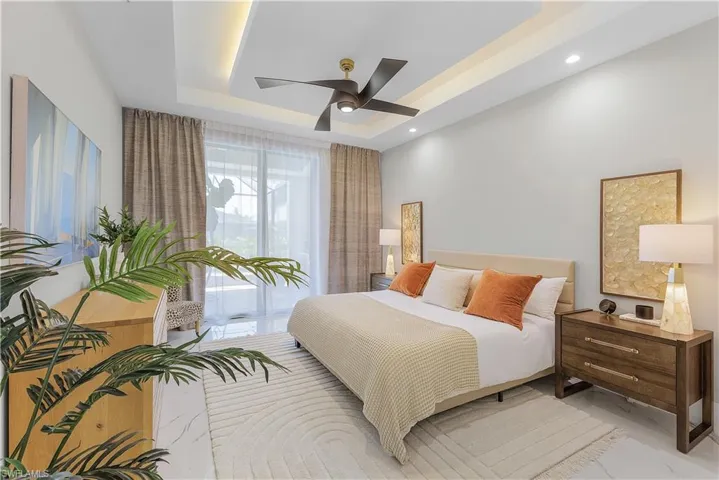 Tiled bedroom featuring a tray ceiling, ceiling fan, and multiple windows