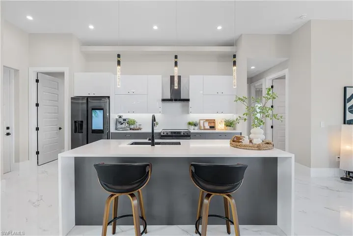 Kitchen with a kitchen island with sink, sink, stainless steel appliances, and white cabinets