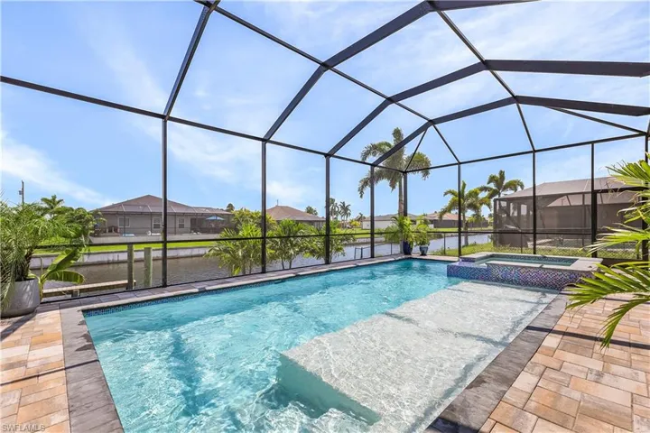 View of swimming pool featuring an in ground hot tub, glass enclosure, and a patio area