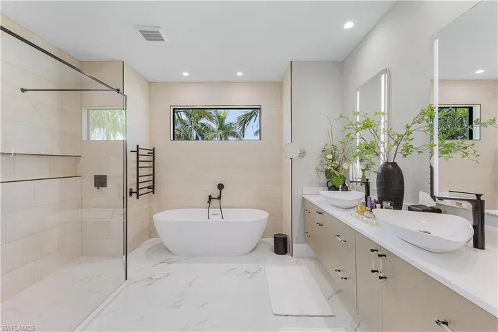 Bathroom with tile walls, tile patterned flooring, double sink vanity, and separate shower and tub