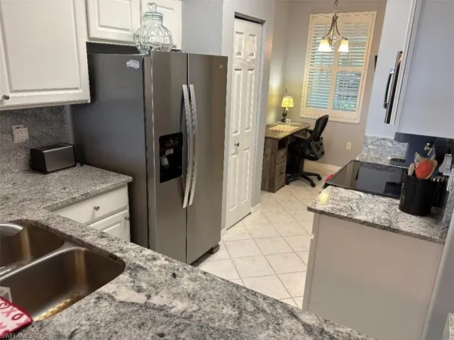 Kitchen featuring light granite counters, pendant lighting, backsplash, and an office area.