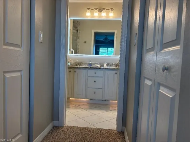 Renovated bathroom counters, lighting and shower.  featuring double vanity, light tile patterned floors, and light colored carpet
