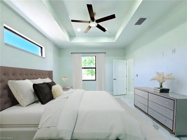 Bedroom featuring marble finish floor, a ceiling fan, baseboards, a tray ceiling, and visible vents