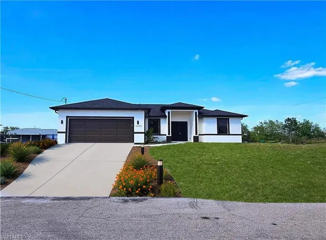 Prairie-style house featuring a garage, stucco siding, concrete driveway, and a front lawn