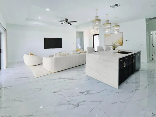 Kitchen with pendant lighting, stainless steel dishwasher, a sink, ceiling fan with notable chandelier, and dark cabinetry