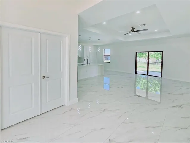 Spare room featuring baseboards, visible vents, marble finish floor, ceiling fan, and a raised ceiling
