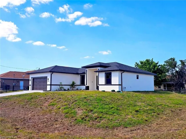 Prairie-style house featuring fence, stucco siding, driveway, a front yard, and a garage