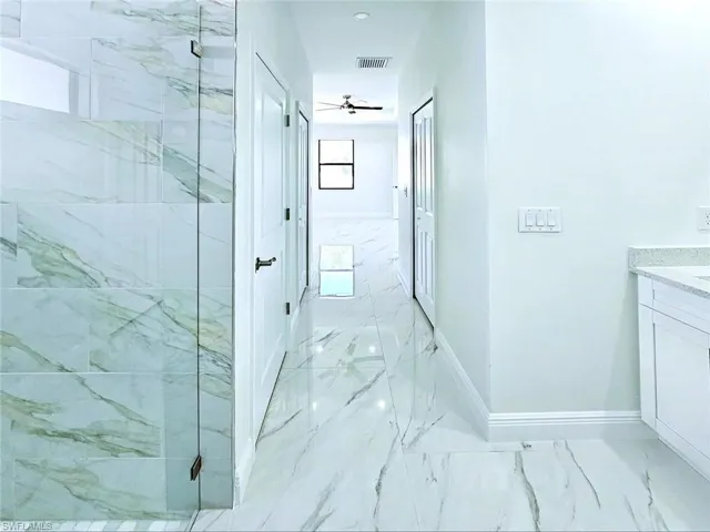Full bath with marble finish floor, baseboards, vanity, and a marble finish shower