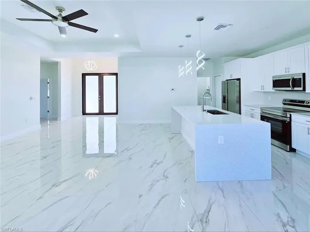 Kitchen featuring visible vents, a sink, baseboards, appliances with stainless steel finishes, and open floor plan