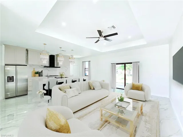 Living room with marble finish floor, visible vents, recessed lighting, a ceiling fan, and a tray ceiling