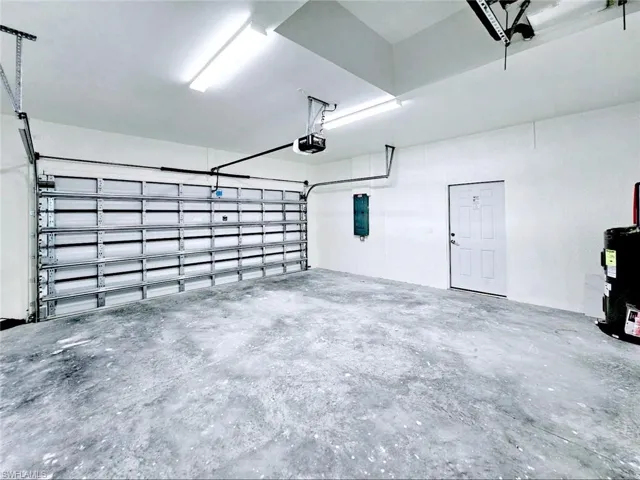 Garage featuring a garage door opener and electric water heater