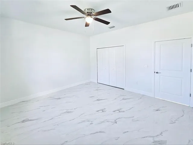 Unfurnished bedroom featuring marble finish floor, baseboards, visible vents, and a closet