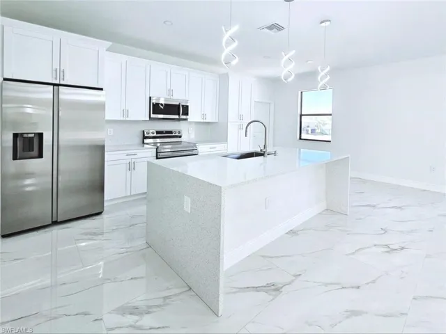 Kitchen with marble finish floor, stainless steel appliances, visible vents, a sink, and baseboards