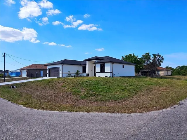 View of front of home with concrete driveway, a front lawn, stucco siding, and a garage