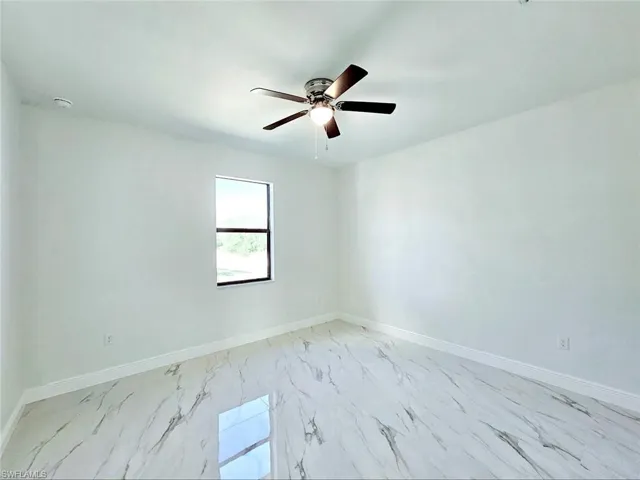 Unfurnished room with marble finish floor, baseboards, and ceiling fan