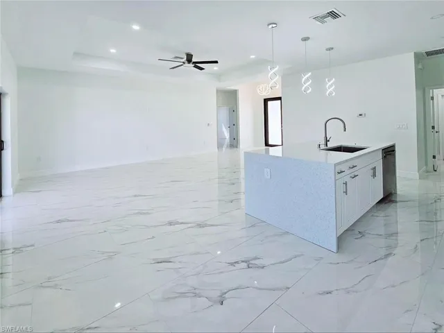 Kitchen with a sink, ceiling fan, a tray ceiling, black dishwasher, and visible vents