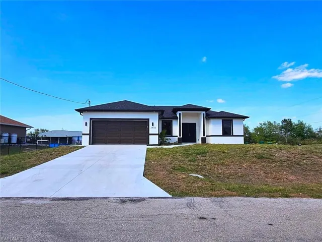Prairie-style house with an attached garage, a front lawn, stucco siding, and driveway