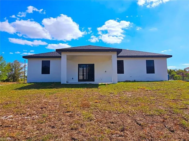 Back of property with a yard and stucco siding
