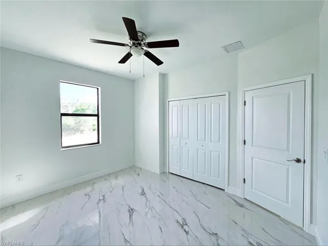 Unfurnished bedroom with a ceiling fan, baseboards, marble finish floor, and a closet